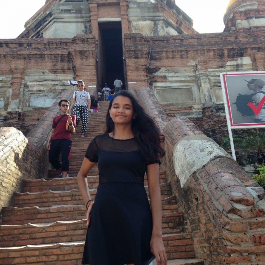Anu stands at the foot of a buddhist temple in Thailand. 