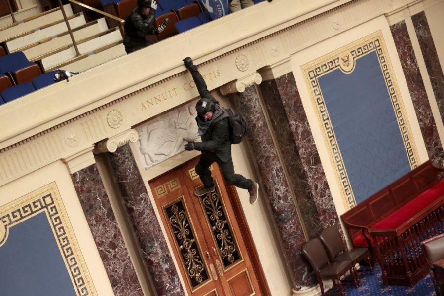 An+extremist+hangs+from+the+balcony+of+the+Senate+chambers.