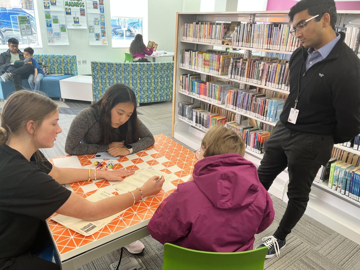 EAST volunteers work through a math worksheet with elementary school students as Akshay Sarda, one of the leaders of EAST, observes. 